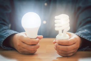 Hands Holding Spiral Bulb And Led Light Bulb, Saving Energy Effi
